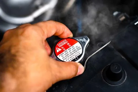 Hand removing the radiator cap while the radiator coolant overheated Stock Photos