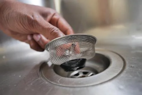 Hand Removing Sink Strainer From Kitchen Drain for Cleaning and Maintenance Stock Photos