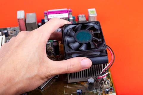 Hand removing an small old CPU cooler from the motherboard Foto stock
