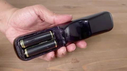Hand removing two AA battery from remote Video stock 345586300