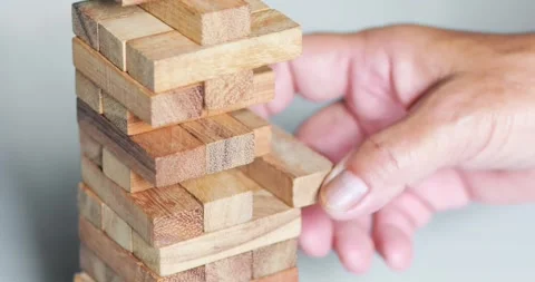 Hand removing a wooden block from a stacking tower game, strategy, decision.. Stock Footage 341557986