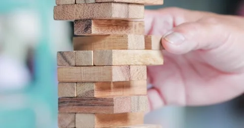 Hand removing a wooden block from a stacking tower game, strategy, decision.. Stock Footage 341810033