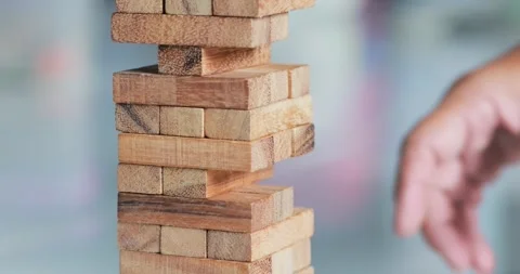 Hand removing a wooden block from a stacking tower game, strategy, decision.. Stock Footage 342217216