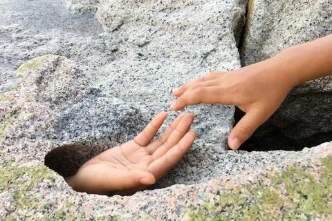 Hand request help from big stone hole. Stock Photos