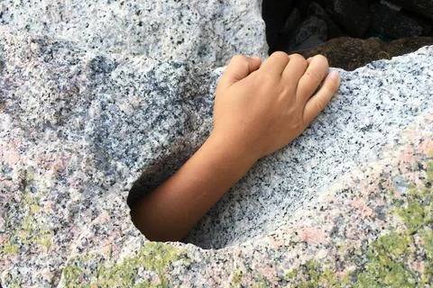 Hand request help from big stone hole. Stock Photos