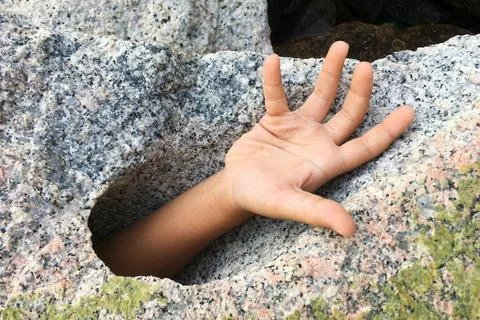 Hand request help from big stone hole. Stock Photos