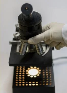 Hand of a researcher while adjusting a microscope. Stock Photos