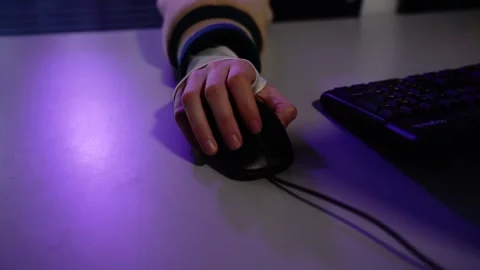 Hand resting on computer mouse at desk in purple light Vídeo Stock 348029498