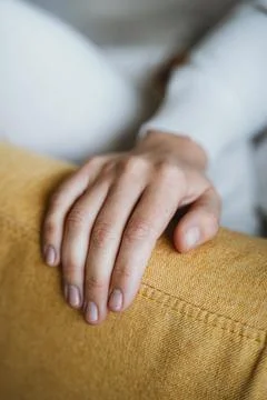 Hand Resting on Yellow Couch Displaying Relaxation 스톡 사진
