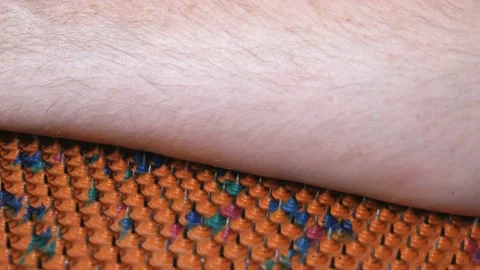 The hand rests on a needle acupuncture mat. Sharp iron needles on a rubber sheet Stock Footage 233328774