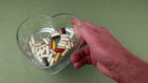 Hand from Right Side Shows a Heart Shape Dish of Supplements Stock Footage 169256810