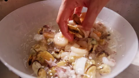 Hand Rinses Raw Squid And Mussels in a Water Filled Bowl at Kitchen Sink, Showin Stock Footage 341973892