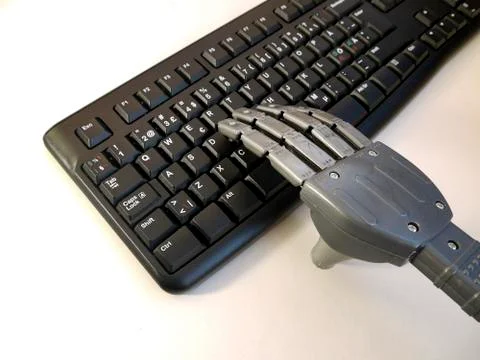 Hand of a robot working on a pc keyboard. Stock Photos