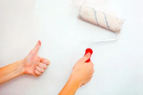Hand with roller brush and hand showing thumb up. Stock Photos