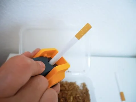 Hand Rolling Cigarette with Orange Rolling Machine, Step-By-Step Tobacco Assembl 스톡 사진