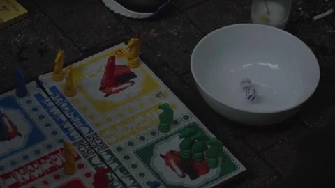 Hand rolling dice and playing Ludo board game on pavement Stock Footage 280565394