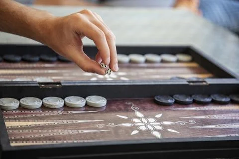 Hand rolling dice in traditional backgammon game close-up Stock Photos