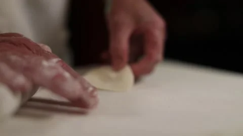 Hand rolling dough to make stuffed Chinese gyoza dumplings - isolated on Video stock 156511854
