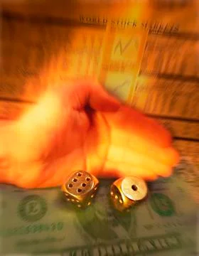 HAND ROLLING PAIR OF DICE WITH FIVE DOLLAR BILL AND STOCK MARKET PRICES Stock Photos