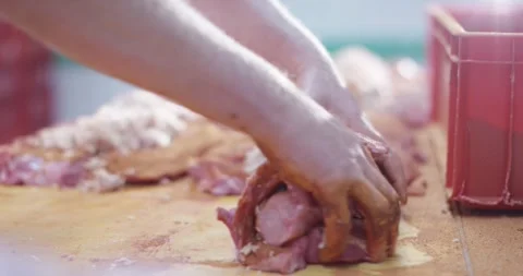 Hand rolling a stuffed raw meat roulade on a wooden work table in a butcher shop Vídeo Stock 339988854