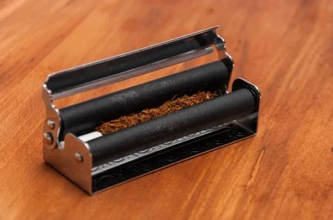 Hand rolling tobacco with the filter in the machine Stock Photos