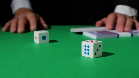 The hand rolls the dice and puts a wad of money on the green gaming table. The e Stock Footage 211288575