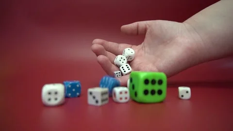The hand rolls different dice on a red background. Stock Footage 320573966