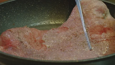 Hand rotates the pork steak fried in a frying pan. steak closeup. Stock Footage 124579002