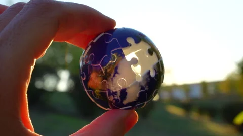 Hand Rotating Puzzle Globe with Sunset Background Stock Footage 295115404