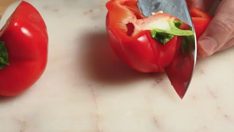 Hand rotating a whole red bell pepper while cutting out the stem Stock Footage 344177227