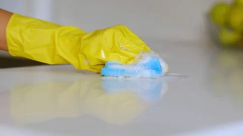Hand with rubber glove cleaning table with sponge and detergent. hand with Stock Footage 138458789