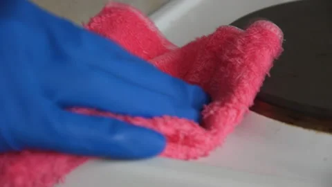 Hand in rubber glove cleans the surface of the electric stove with a pink ki Video stock 127060904