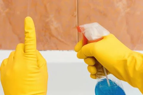 Hand in rubber gloves indicates mold in the bathroom Stock Photos