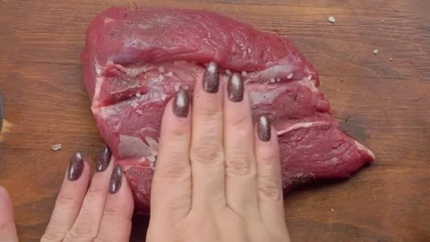 Hand rubbing black pepper on a piece of raw beef Stock Footage 295656759