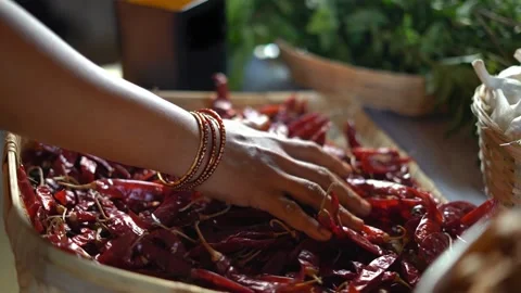 A hand running through a heap of dried red chillies in a basket Stock Footage 340958567