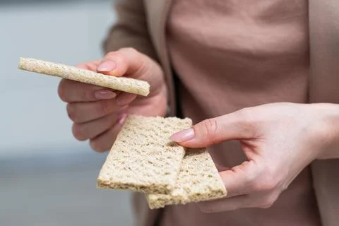 Hand with salty cracker, crispy appetizer, rectangle shape cookie. Isolated on Stock Photos