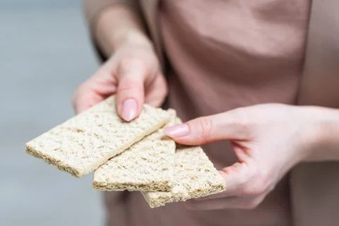 Hand with salty cracker, crispy appetizer, rectangle shape cookie. Isolated on Stock Photos