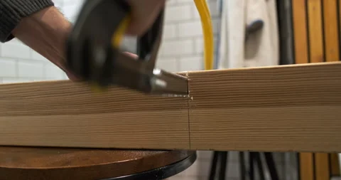 Hand saw stuck, thick square wooden beam, back view, close-up, indoors. Concept 動画素材 256289687