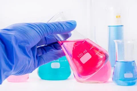 Hand of scientist in protective gloves hold chemical Erlenmeyer flask Stock Photos