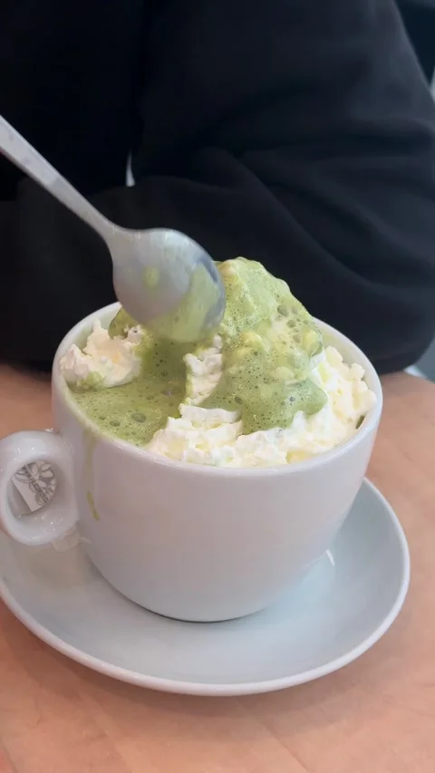 Hand scooping frothy green matcha latte beverage, creamy warm drink with rich Stock Footage 333163716
