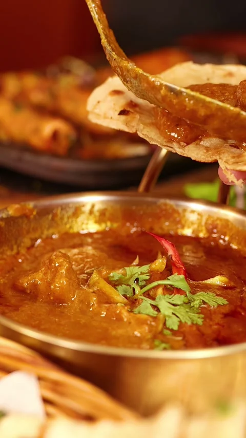 Hand Scooping Indian Curry onto Naan Bread in Bangkok Restaurant Stock Footage 340183296