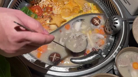 Hand Scooping Meat from a Divided Hot Pot Видео 346738941