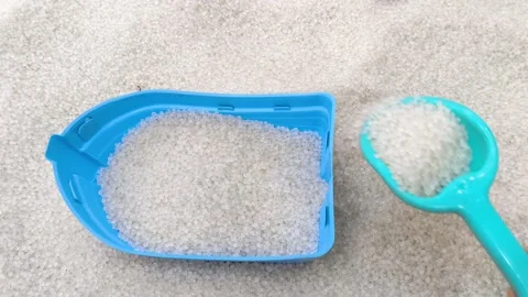 Hand Scooping White Plastic Pellets into Blue Toy Boat Stock Footage 323342436