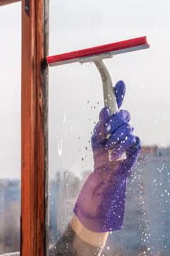 A hand scrapes the soap suds off the window pane Stock Photos