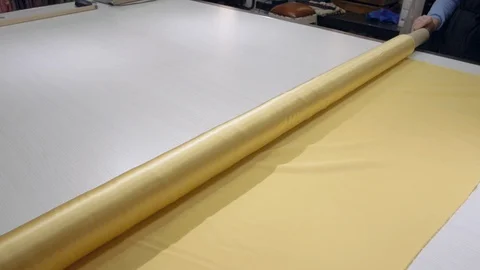 Hand screen rolling up yellow silk fabric on the table, textile fashion industry Stock Footage 109329435