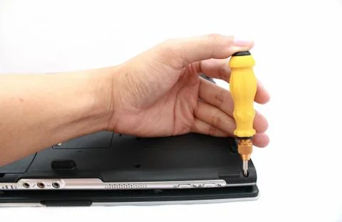 A hand with screwdriver fixing a computer. Stock Photos