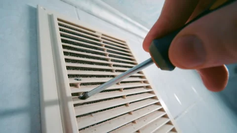 Hand with Screwdriver Removing Screws from Dusty Ventilation Grille | HVAC Vidéo 333485145