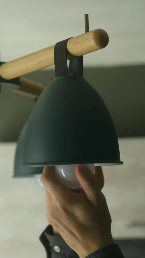 Hand screwing led light bulb into modern lamp fixture Stock Footage 321738569