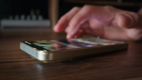 Hand Scrolling on Screen of Smartphone Lying on Wooden Table Close Up Vídeo Stock 339208629