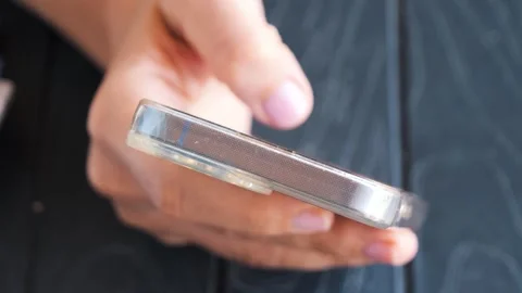 Hand scrolling a smartphone screen outdoors during a sunny afternoon Vidéo 287642680